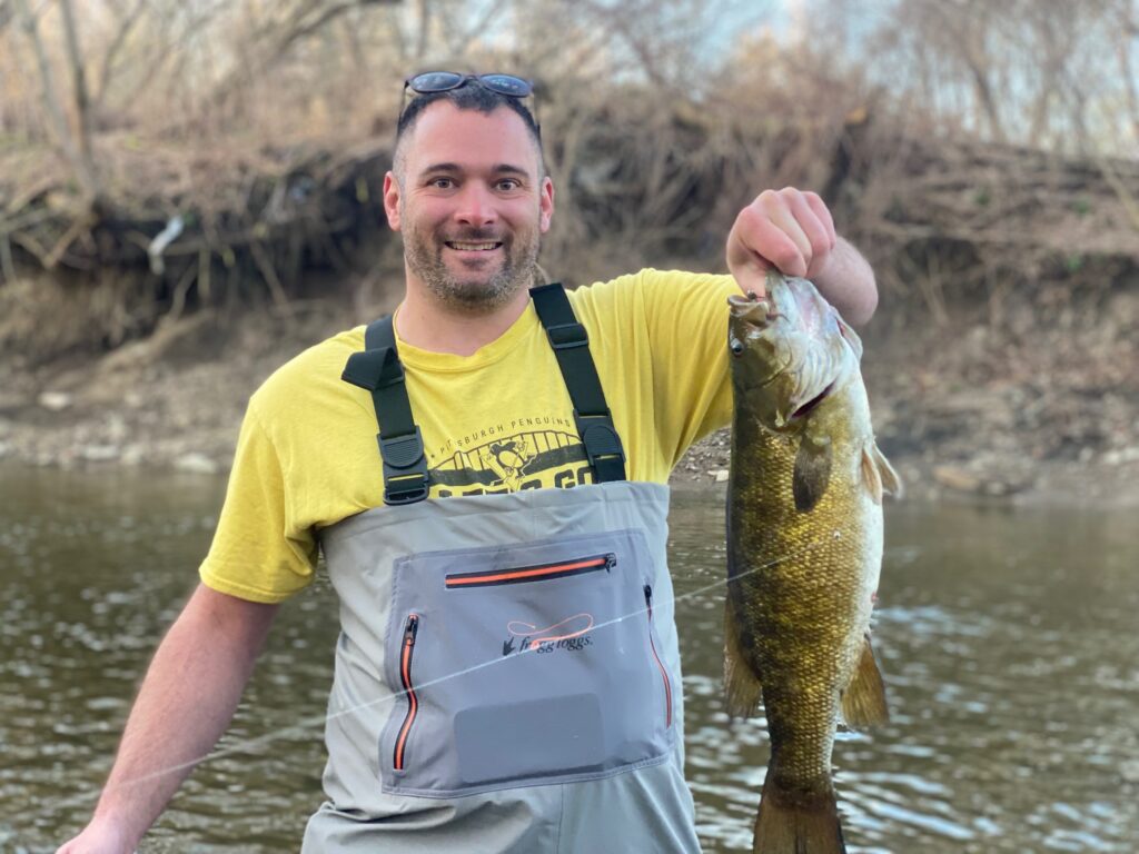 guided client holding a trophy sized smallmouth bass caught on conneaut creek in conneaut ohio on fly fishing trip with keystone anglers guide service