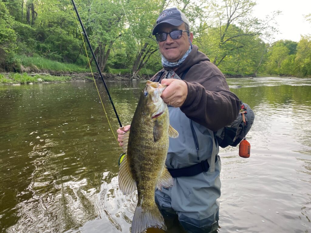 guided client holding a trophy lake erie lake run smallmouth bass caught on fly fishing trip on elk creek in erie pennsylvania with keystone anglers guide service