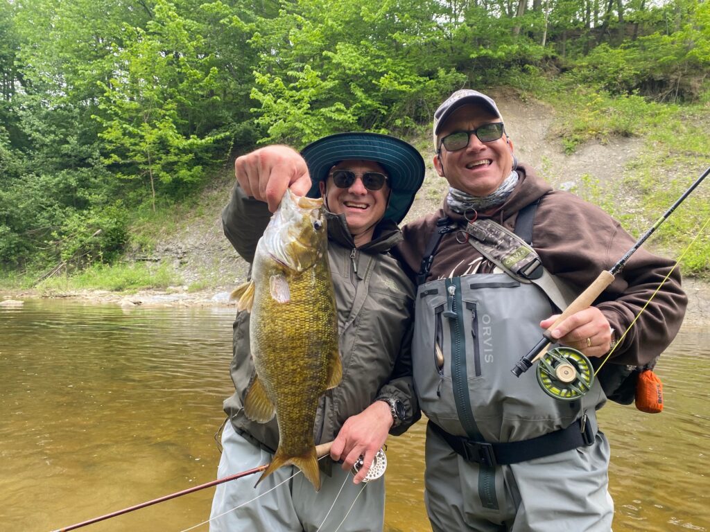 guided clients holding a lake erie lake run smallmouth bass caught during a fly fishing trip on elk creek in erie pennsylvania